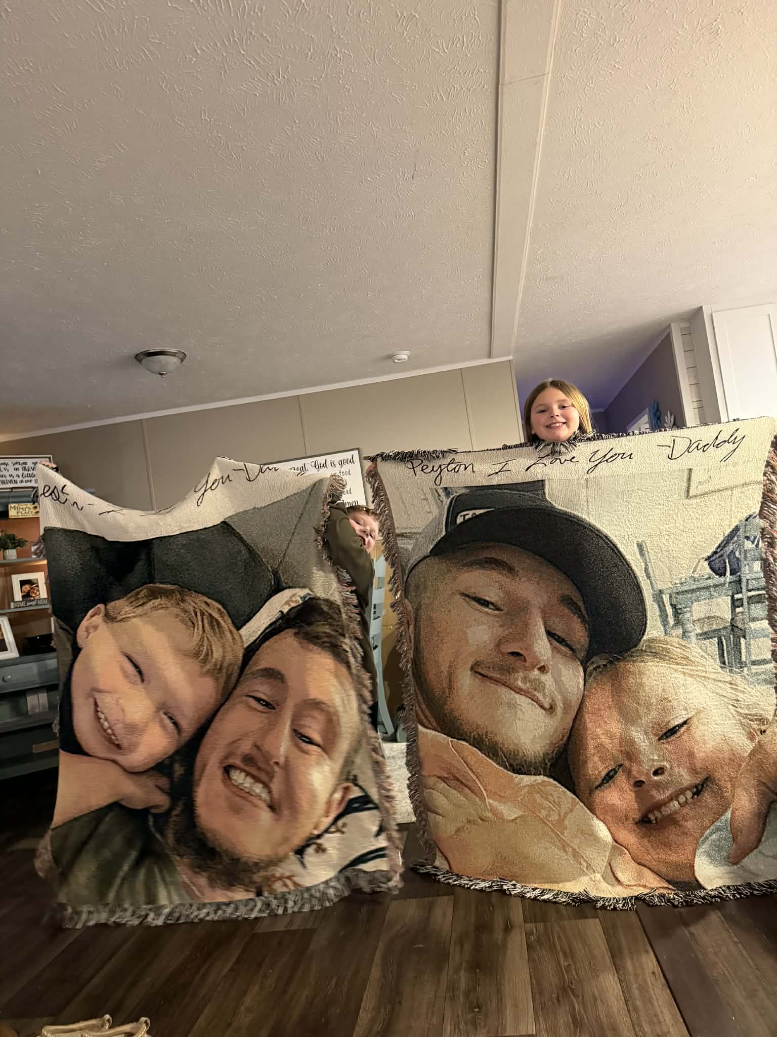 Two custom blankets with woven faces held up by two children peaking out from behind.
